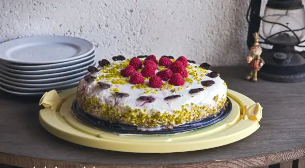 Himbeer Torte mit frischen Beeren, gehackten Pistazien und Schokoladenherzen verziert. Ein Genuss für jeden Anlass.