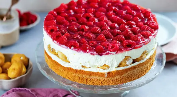 Eine köstliche Windbeuteltorte mit Himbeeren, geschichtet mit Sahne und Biskuit, verlockt zum Genuss.