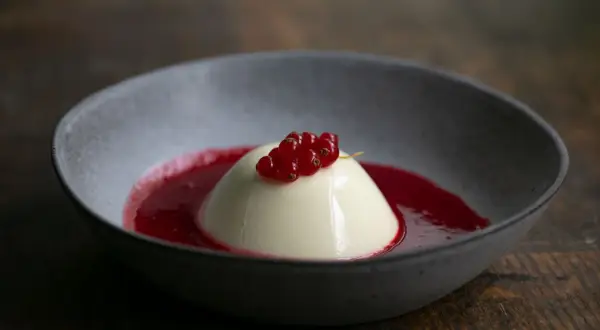 Cremige Panna Cotta mit roter Johannisbeersauce, ein köstliches Rezept für ein leichtes Dessert.