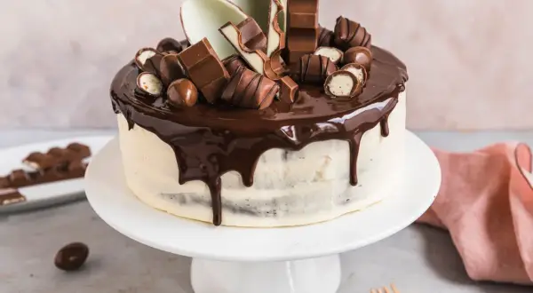 Eine köstliche Kinderschokolade Torte mit Schokoladenglasur und vielen Schokoriegeln und Kugeln verziert.