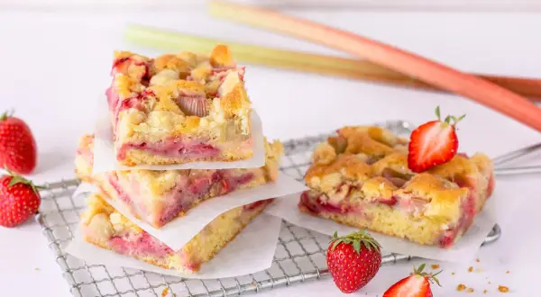 Saftiger Erdbeer Rhabarber Kuchen mit Streuseln, garniert mit frischen Erdbeeren.