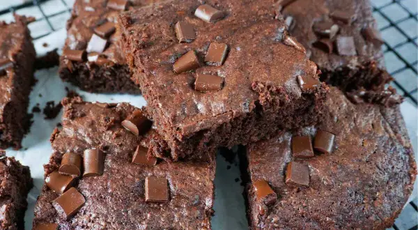Saftige Zucchini-Brownies mit Schokoladenstückchen, die auf einem Gitterrost liegen.