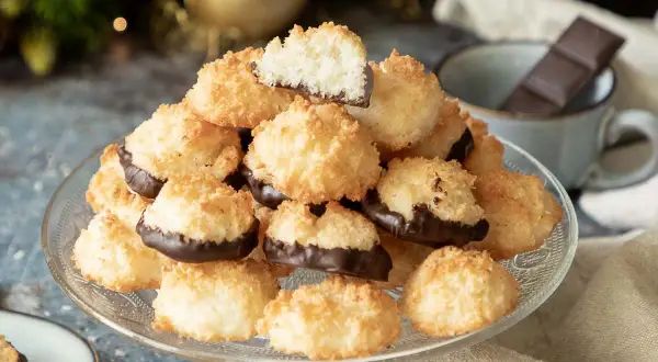 Ein Berg goldbrauner Kokosmakronen, die untere Hälfte in dunkle Schokolade getaucht. Perfekt für ein einfaches Kokosmakronen Rezept.