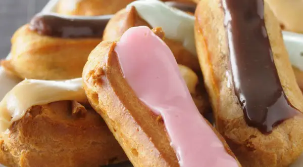 Bunte Éclairs mit Schokoladen-, Erdbeer- und Vanilleglasur. Ein köstliches Éclair-Rezept zum Nachbacken.