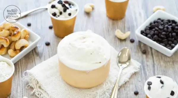 Cremiges Vanilleeis ohne Ei, serviert in Bechern, mit Cashews und Schokodrops daneben.