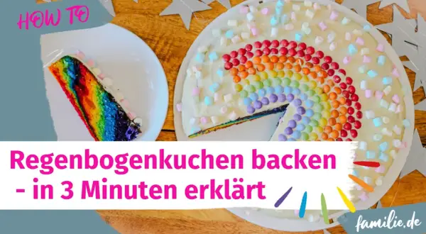 Ein bunter Regenbogenkuchen, verziert mit Marshmallows und bunten Smarties. Ein Stück ist bereits angeschnitten.
