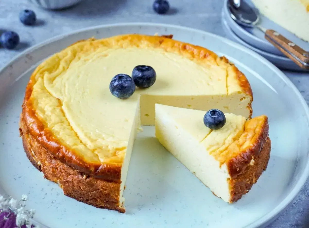 Ein cremiger Käsekuchen, perfekt für Diabetiker, mit frischen Blaubeeren garniert. Ein Stück wurde bereits entnommen.