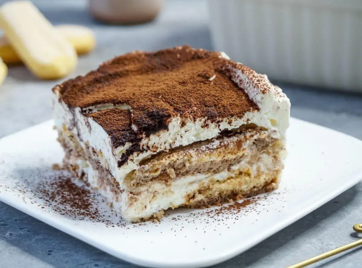 Ein Stück cremiges Tiramisu, bestäubt mit Kakao, perfekt für kleine Genießer.