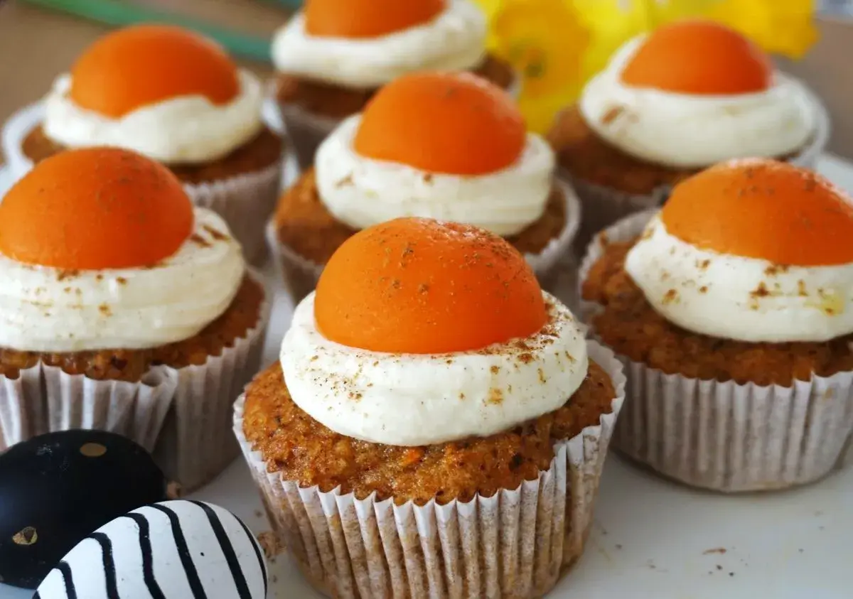 Leckere Oster Muffins mit cremiger Glasur und orangefarbener Deko.