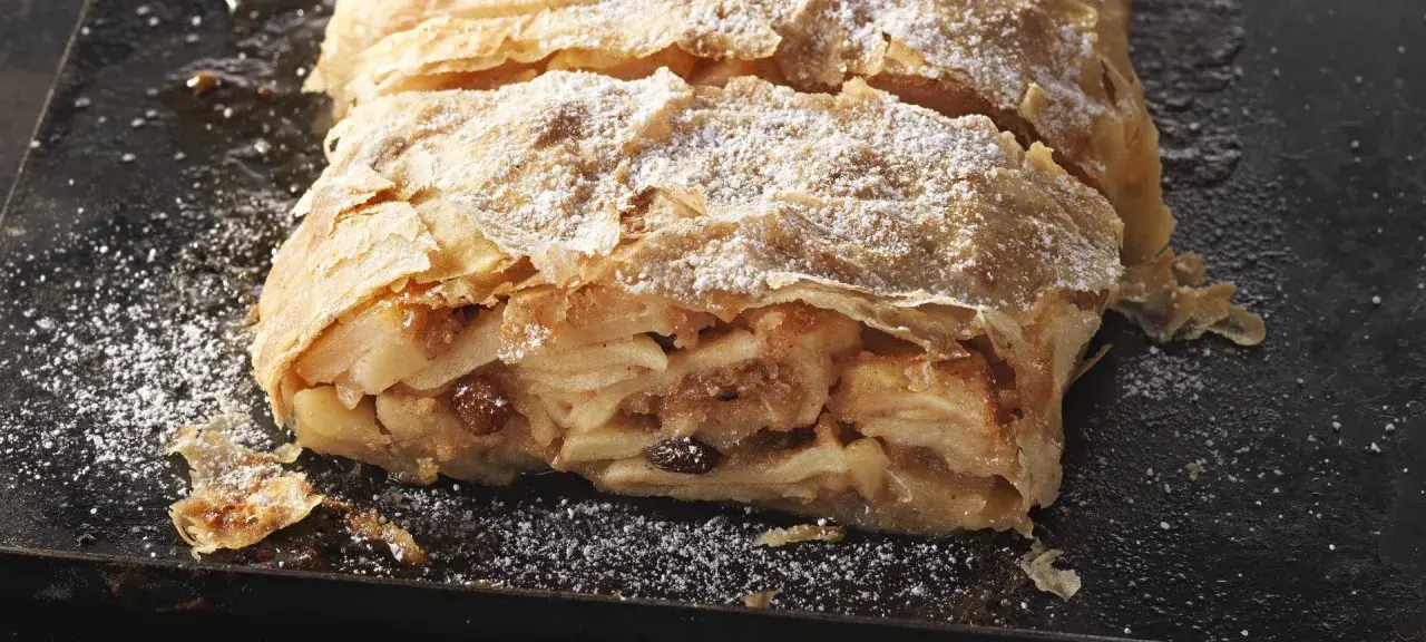 Ein saftiger Apfelstrudel, bestäubt mit Puderzucker, wartet darauf, nach diesem Rezept gebacken zu werden.