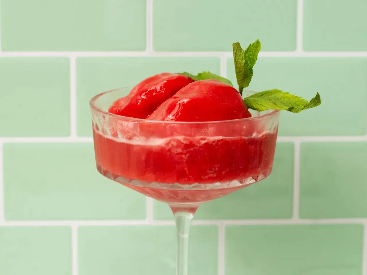 Erfrischendes Wassermelonen Sorbet in einem eleganten Glas, garniert mit Minze. Perfekt für heiße Tage.
