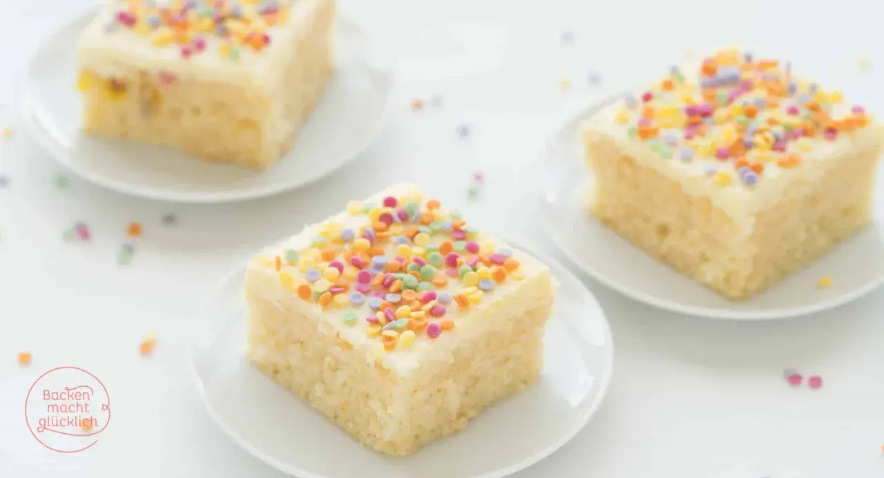 Drei Stücke saftiger konfetti kuchen mit weißer Glasur und bunten Streuseln auf weißen Tellern.