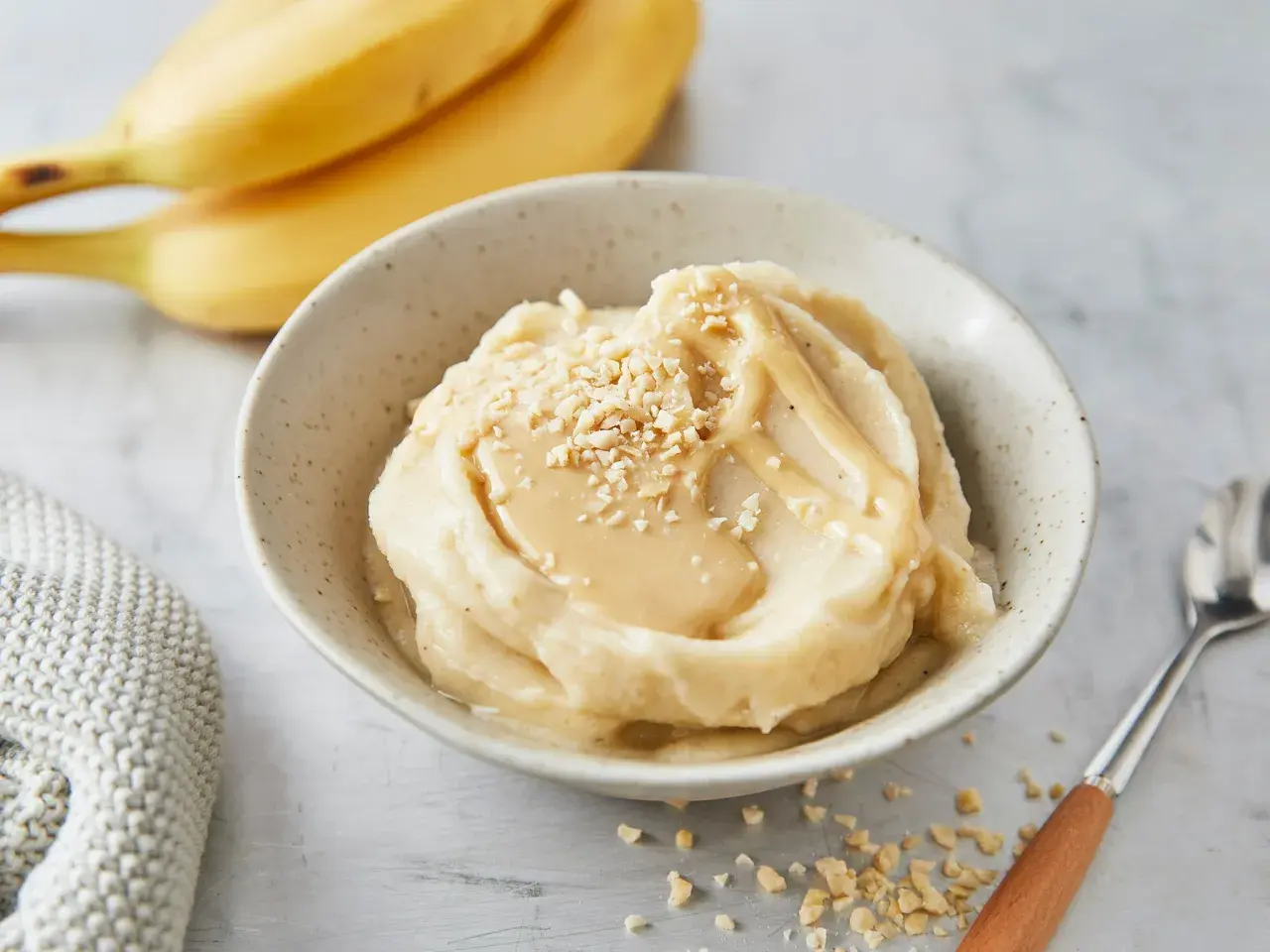 Cremiges italienisches Bananeneis mit Karamellsauce und gehackten Nüssen, garniert mit frischen Bananen.
