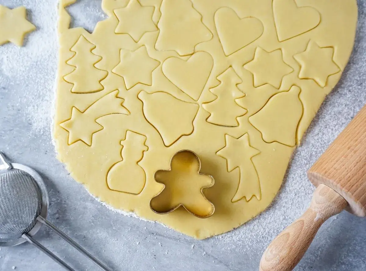 Ausgestochener Teig für Weihnachtsplätzchen mit Sternen, Herzen, Tannenbäumen und Schneemännern. Ein Ausstecher-Rezept für Spaß in der Küche.