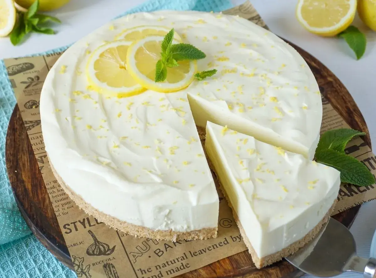 Cremige Philadelphia Torte mit Zitronenscheiben und Minze, ein Stück wurde bereits entnommen.