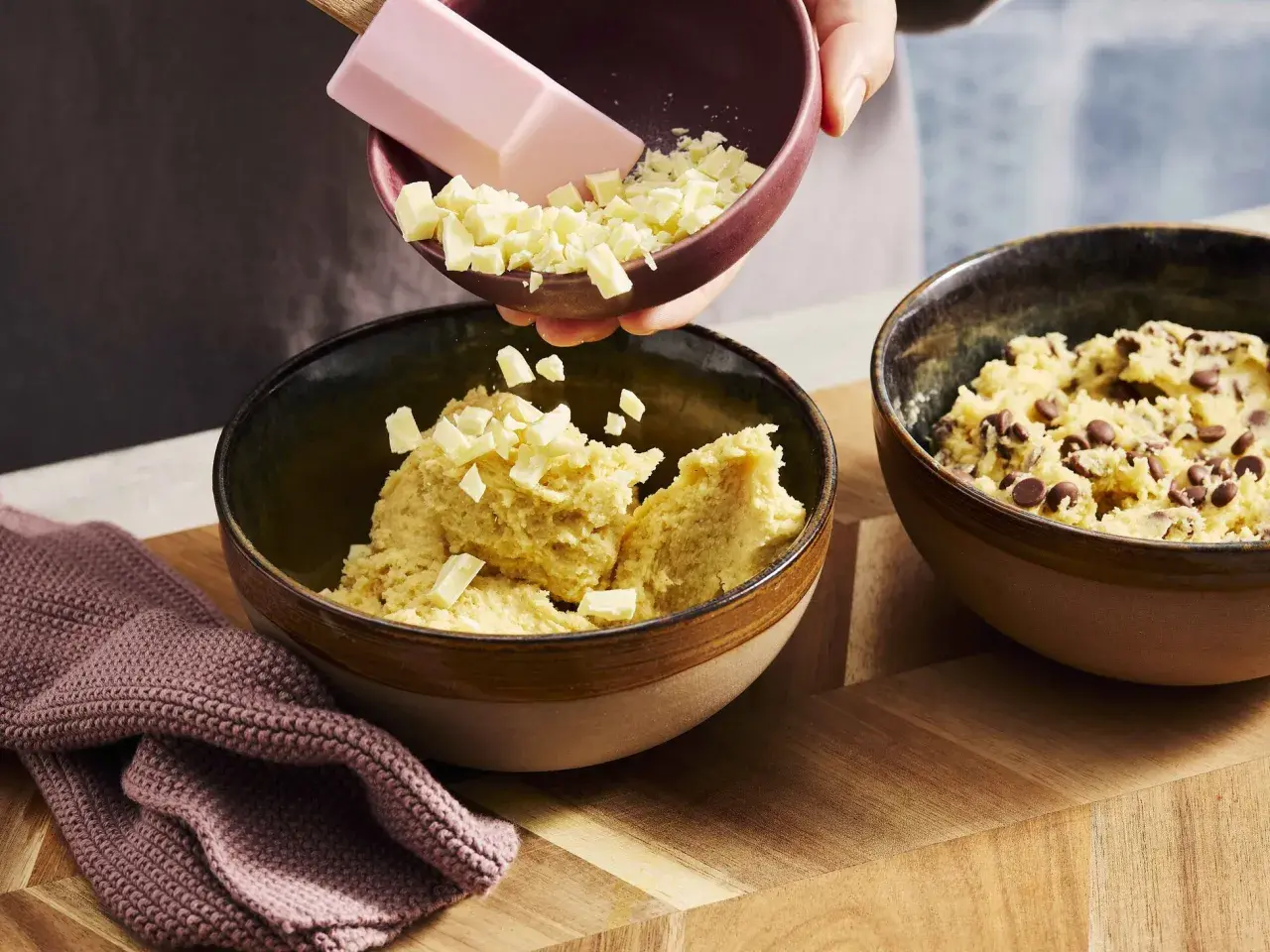 Zutaten für ein Crumble Cookie Rezept werden in Schüsseln gegeben: Teig mit Schokostückchen und weißer Schokolade.