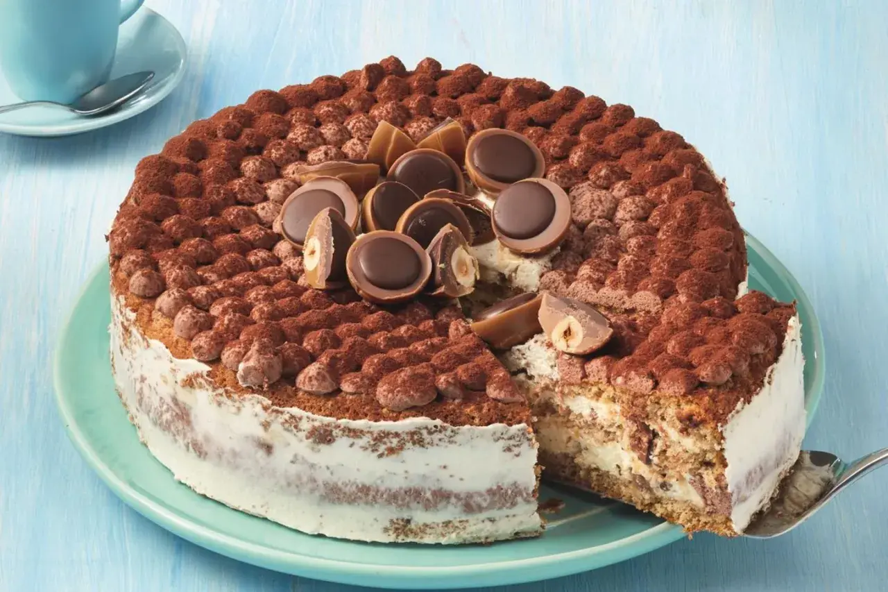 Eine köstliche Toffifee Torte, verziert mit Kakao und Toffifee-Pralinen, wird angeschnitten.