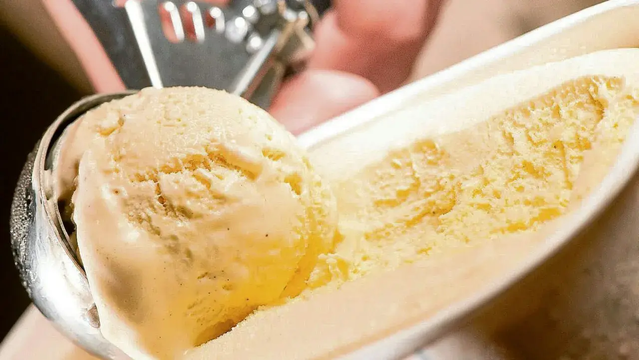 Cremiges Vanilleeis wird mit einer Eiskugelportionierer aus einer Schale gehoben. Ein perfektes Vanilleeis Rezept für heiße Tage.