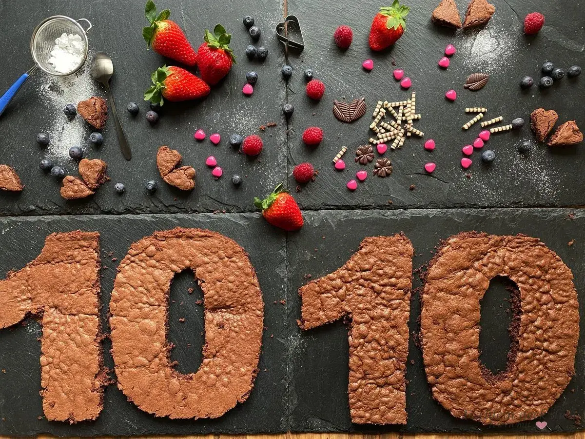 Zahlentorte mit Biskuitboden in Form einer 10, dekoriert mit Erdbeeren, Blaubeeren und Schokoladenherzen.