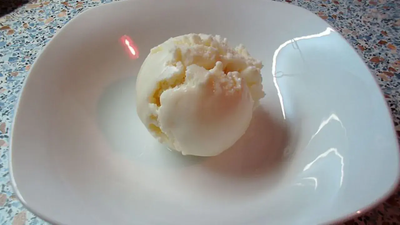 Ein Löffel cremiges Eis aus Quark in einer weißen Schale.