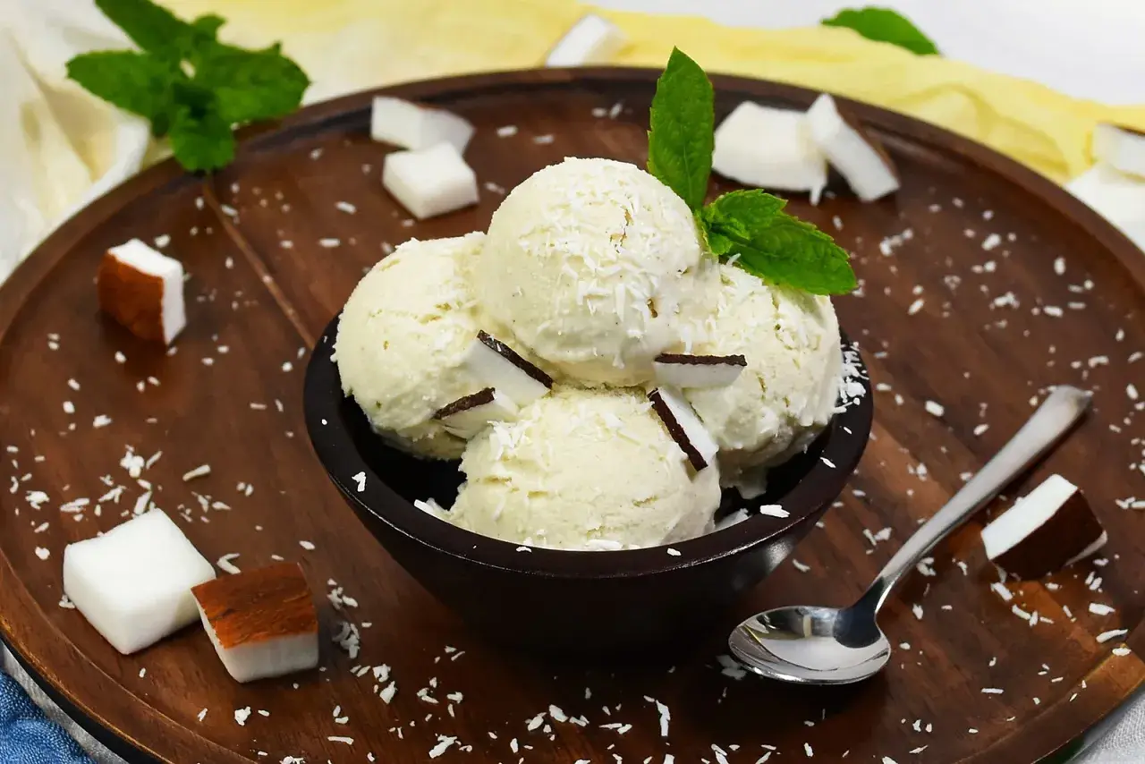 Schüssel mit Kokosnuss-Eis, garniert mit Kokosraspeln und Minze. Perfekt, um Kokosnuss Eis selber machen zu wollen!