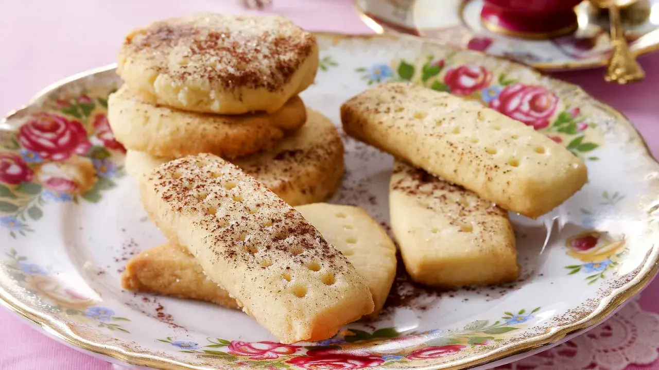 Leckeres Shortbread-Rezept: goldbraune Kekse, rund und rechteckig, mit Zimt und Zucker bestreut, auf einem floralen Teller.
