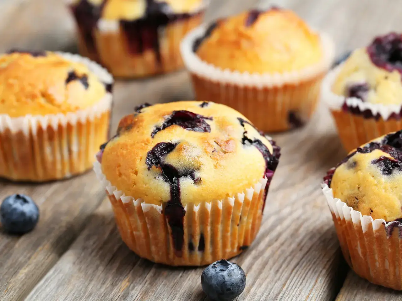 Saftige Blaubeermuffins, perfekt für ein Blaubeermuffins Rezept. Frisch gebacken und auf rustikalem Holz angerichtet.