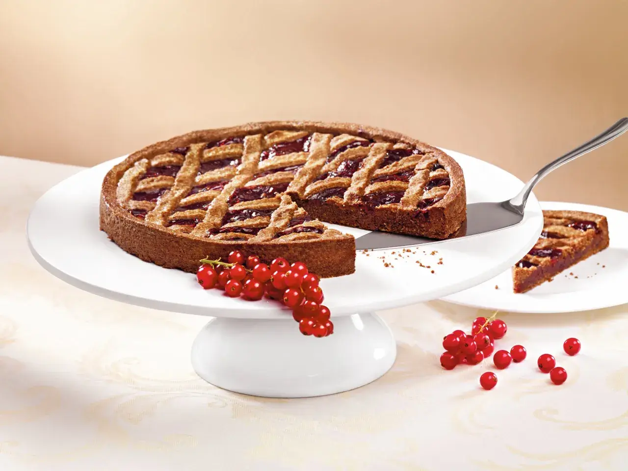 Eine köstliche Linzer Torte mit Gittermuster und roter Johannisbeerfüllung, garniert mit frischen Beeren.