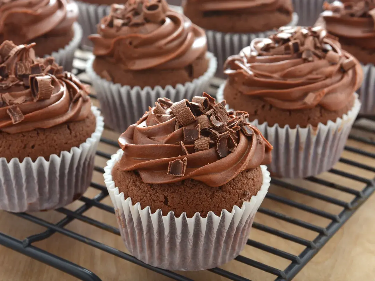 Schoko cupcakes mit cremiger Schokoladenfüllung und Schokostreuseln, auf einem Gitterrost.