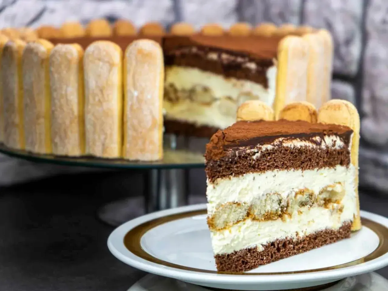 Ein köstliches Stück Tiramisu Torte mit Löffelbiskuits und Kakao bestäubt.