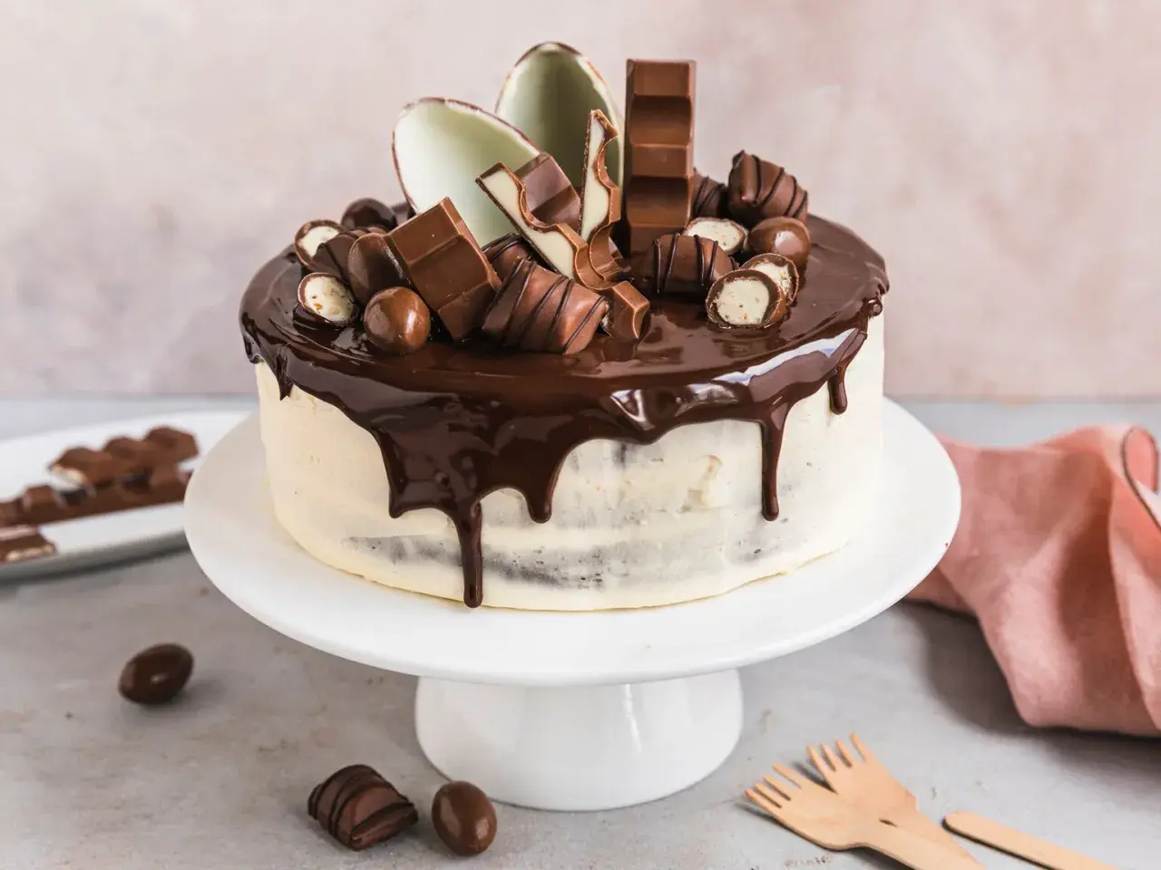 Eine köstliche Kinderschokolade Torte mit Schokoladenglasur und vielen Schokoriegeln und Kugeln verziert.