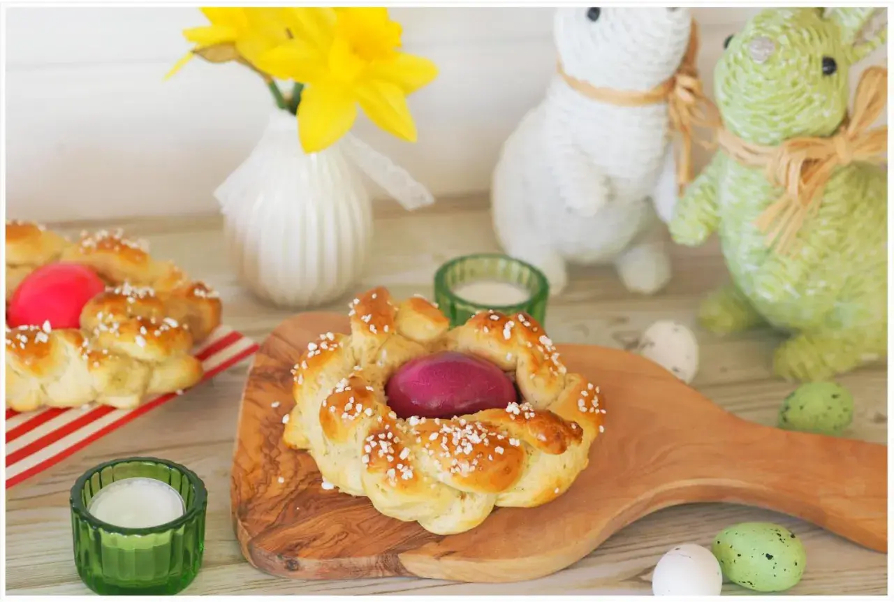 Zwei geflochtene Osterkränze mit gefärbten Eiern, bereit zum Osterfrühstück. Das Backen von Osterkränzen ist eine schöne Tradition.
