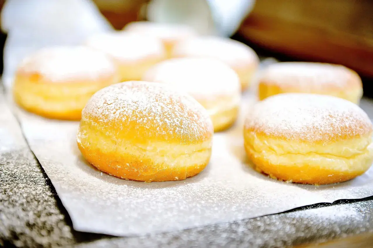 Frisch gebackene Krapfen, mit Puderzucker bestäubt, warten auf das Krapfen Rezept.