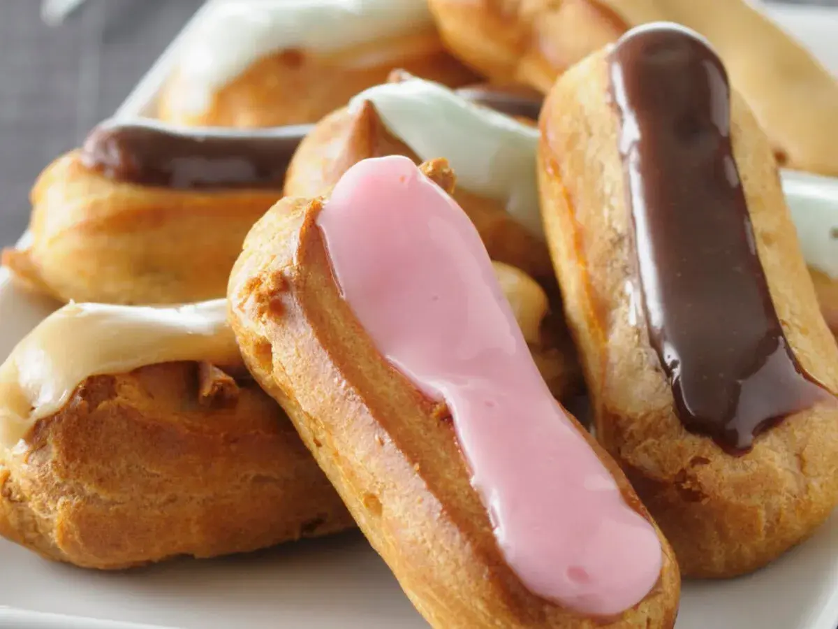 Bunte Éclairs mit Schokoladen-, Erdbeer- und Vanilleglasur. Ein köstliches Éclair-Rezept zum Nachbacken.