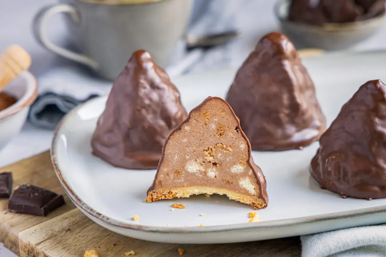 Schokoladen-Desserts, die an Granatsplitter erinnern, mit einem Stück, das die cremige Füllung mit Keksstücken zeigt. Ein köstliches Granatsplitter Rezept.