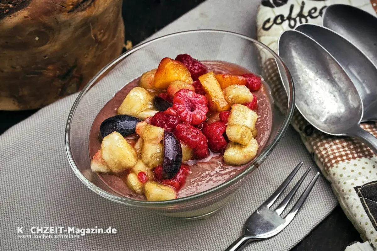 Schüssel mit cremigem Dessert und frischem Obstsalat aus Himbeeren, Bananen und Aprikosen. Perfekt für ein leichtes obstsalat rezept.
