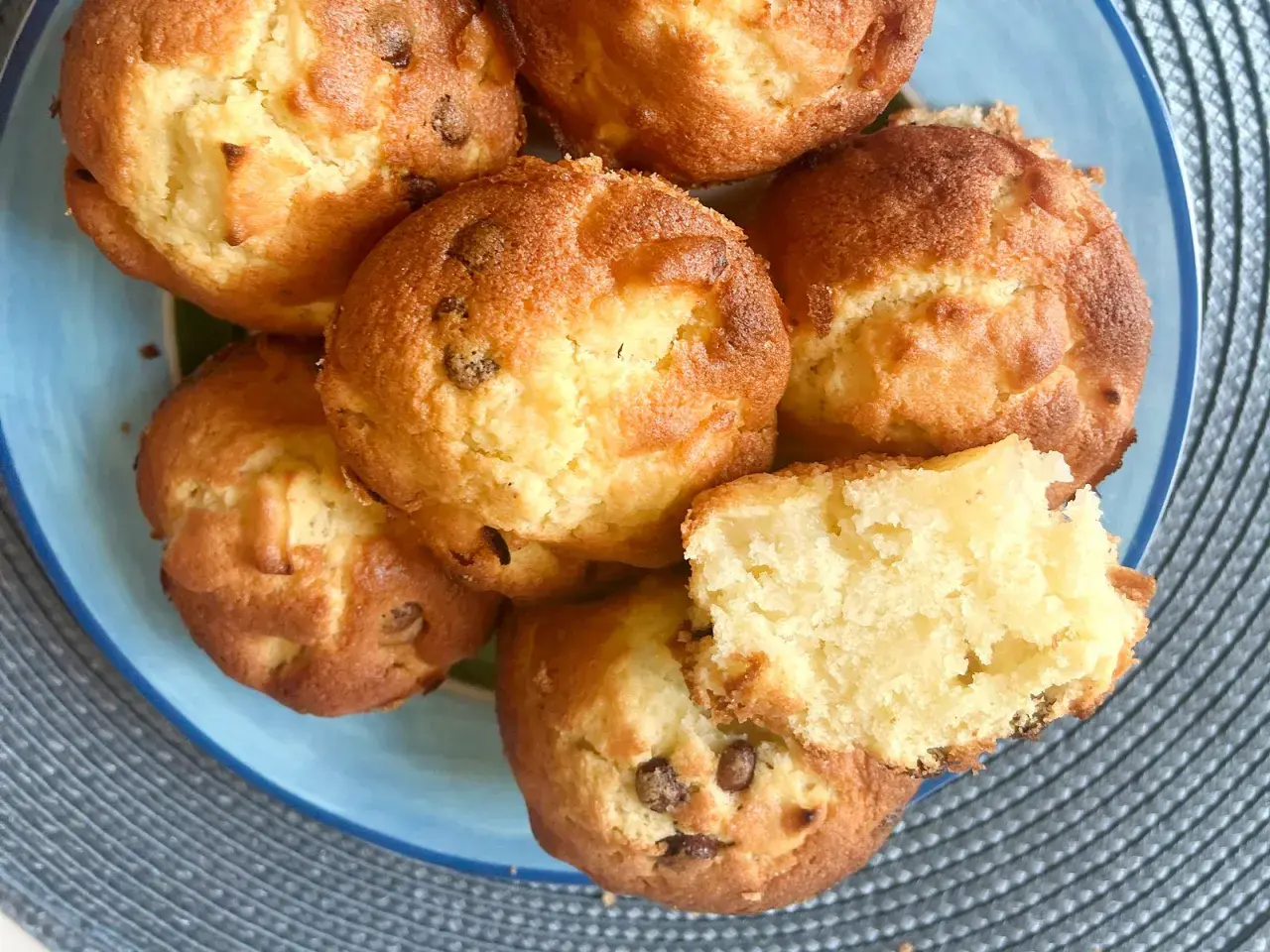 Saftige apfel muffins mit Schokoladenstückchen auf einem blauen Teller. Einer ist zerbrochen und zeigt das weiche Innere.
