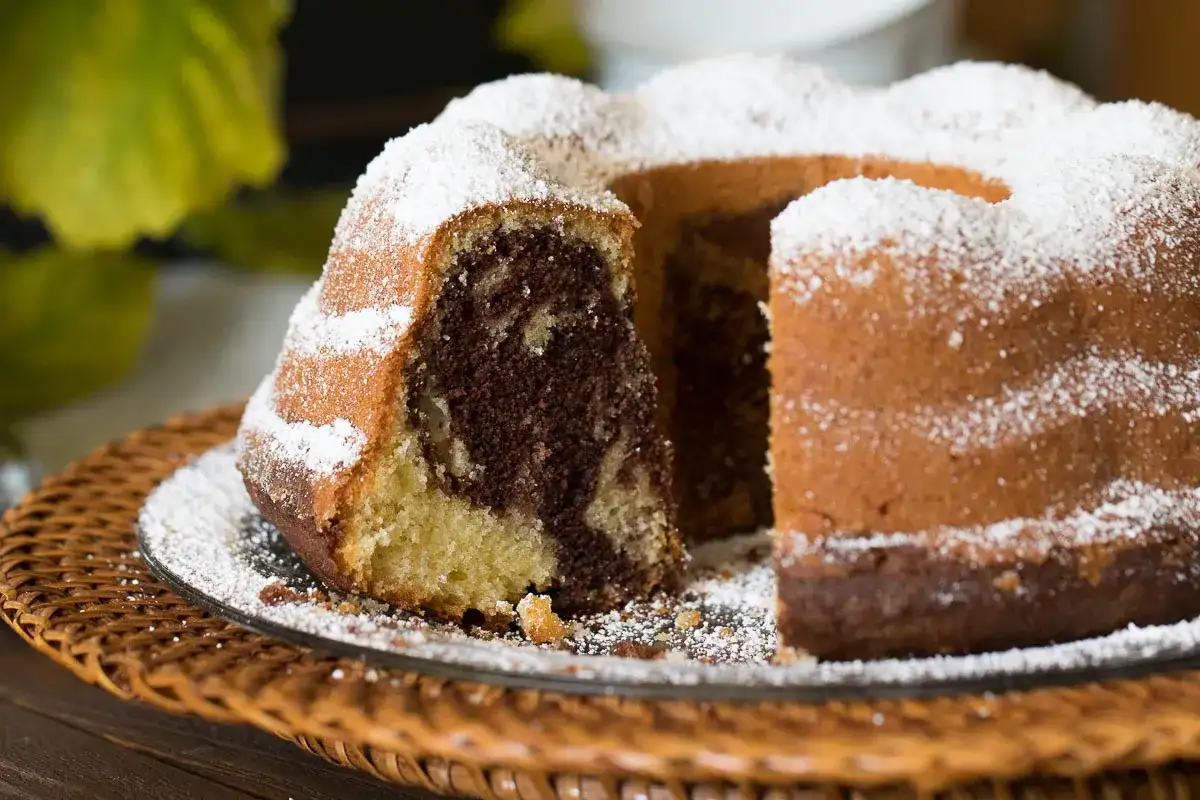 Ein saftiger Gugelhupf Marmor, bestäubt mit Puderzucker, wartet auf seinen Anschnitt.