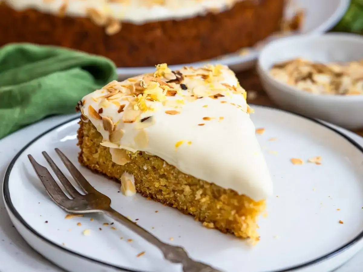 Ein saftiger karottenkuchen mit Frischkäse-Frosting, garniert mit Mandelsplittern und Zitronenschale. Perfekt für jeden Anlass!