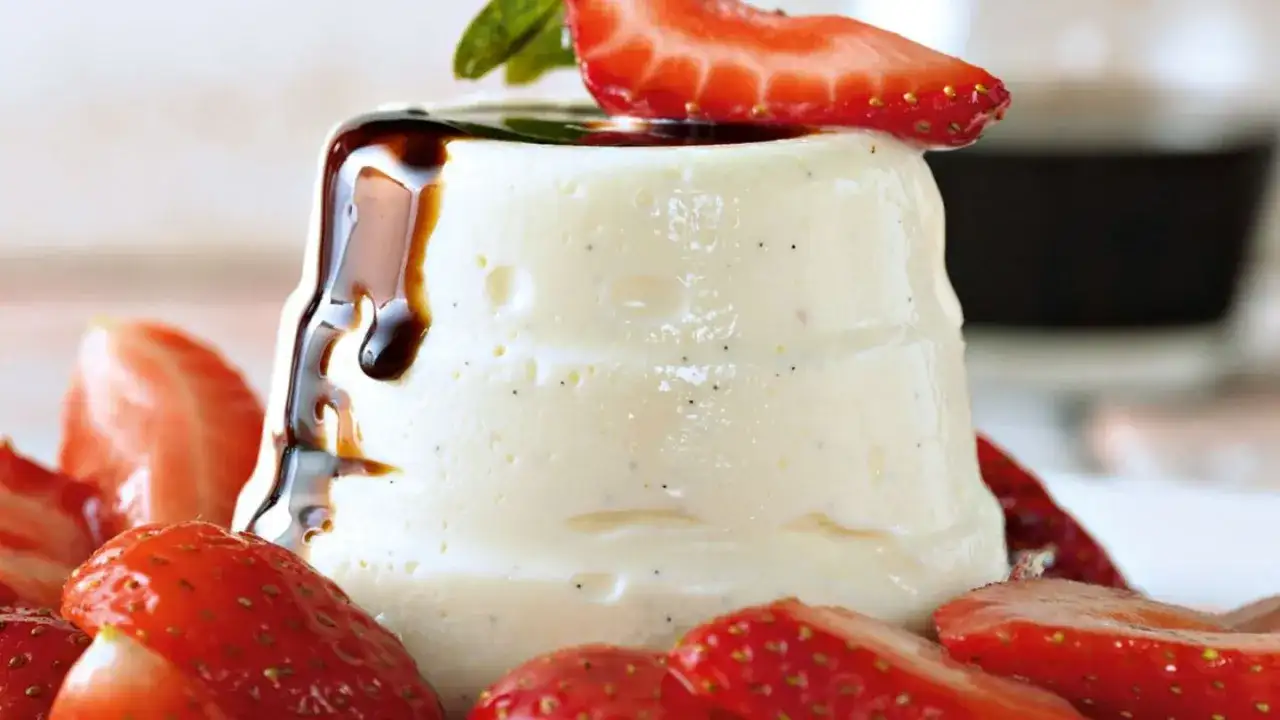 Cremige Panna Cotta mit Erdbeeren und dunklem Sirup, garniert mit Minze. Ein süßer Genuss.
