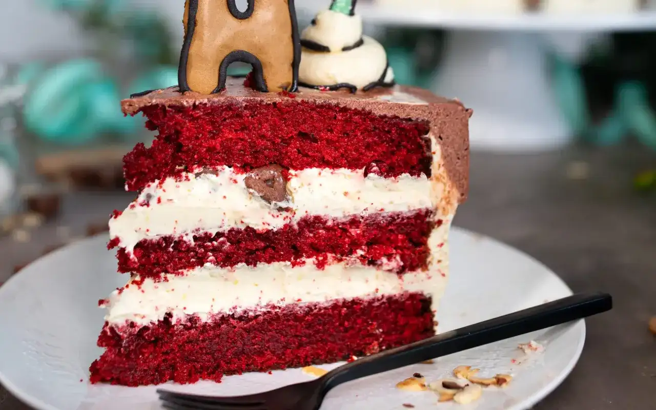 Ein saftiges Stück red velvet Kuchen mit cremiger Füllung und Schokoladenglasur, dekoriert mit Lebkuchenfiguren.