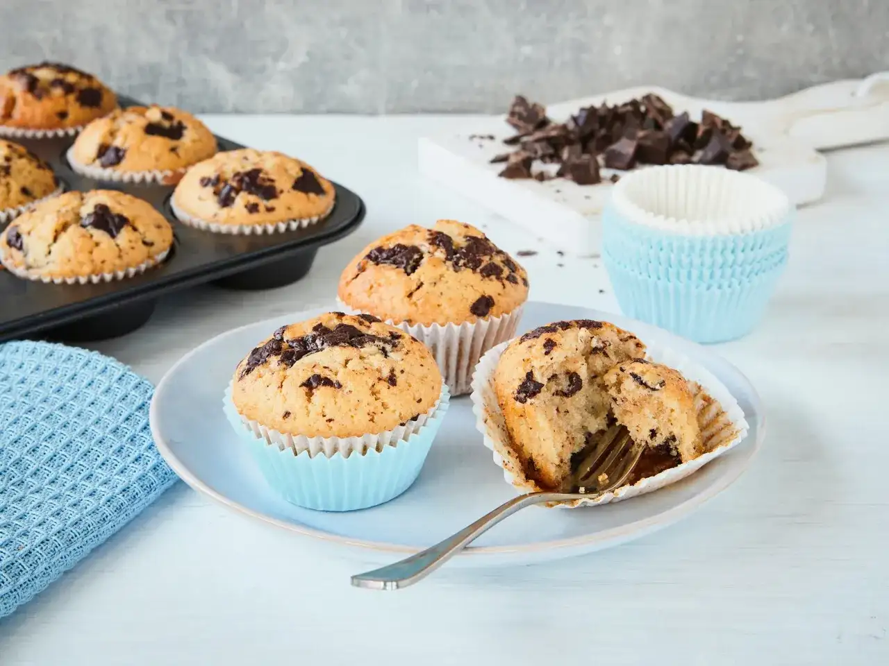 Schokoladenmuffins, frisch gebacken nach einem einfachen Muffins Rezept. Ein Muffin ist angeschnitten und zeigt die saftige Krume.