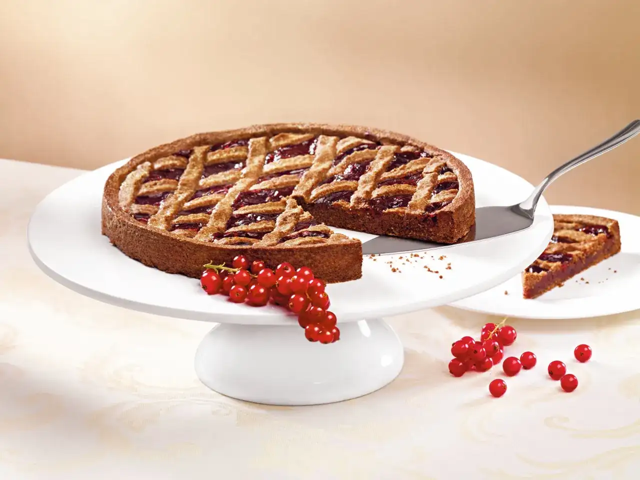 Eine köstliche Linzer Torte mit Gittermuster und roter Johannisbeerfüllung, garniert mit frischen Beeren.