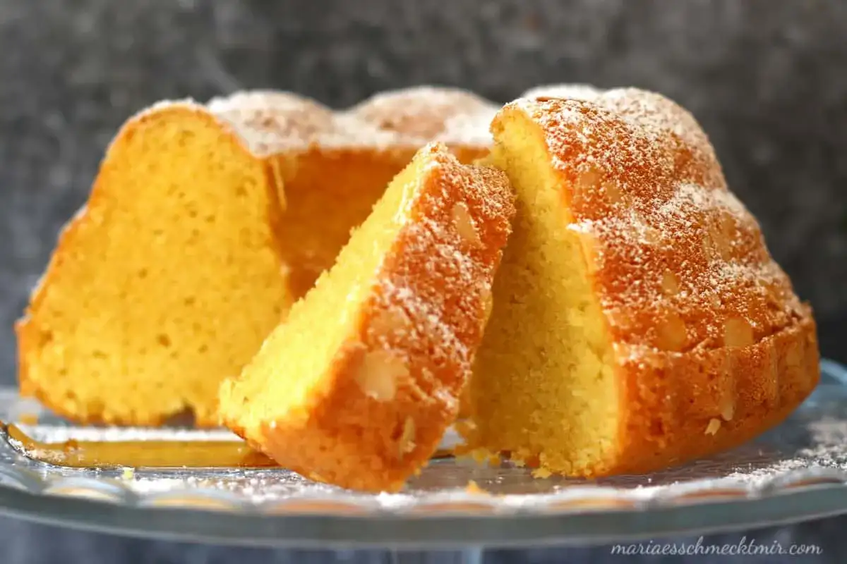 Ein saftiger Kuchen mit vielen Eiern, bestäubt mit Puderzucker, auf einem Glasständer.