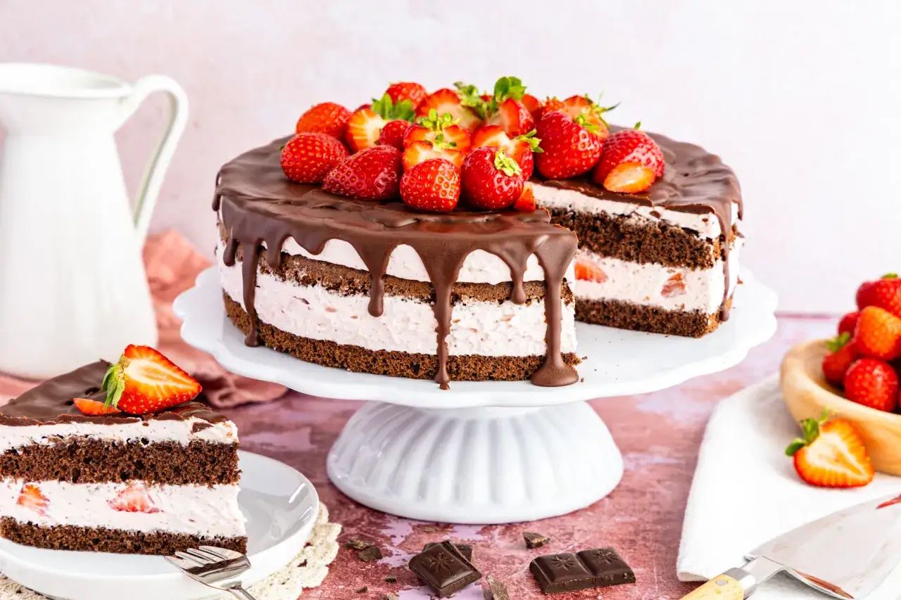 Eine köstliche Erdbeer Schoko Torte mit frischen Erdbeeren und Schokoladenglasur, auf einem weißen Tortenständer präsentiert.