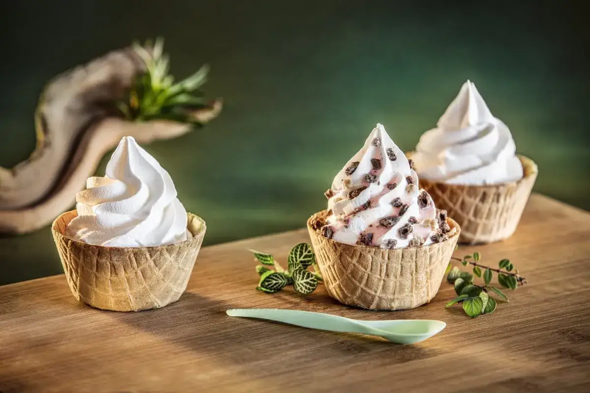 So lecker! Drei Softeis-Variationen im Waffelbecher, perfekt zum Softeis selber machen. Ein grüner Löffel liegt bereit.