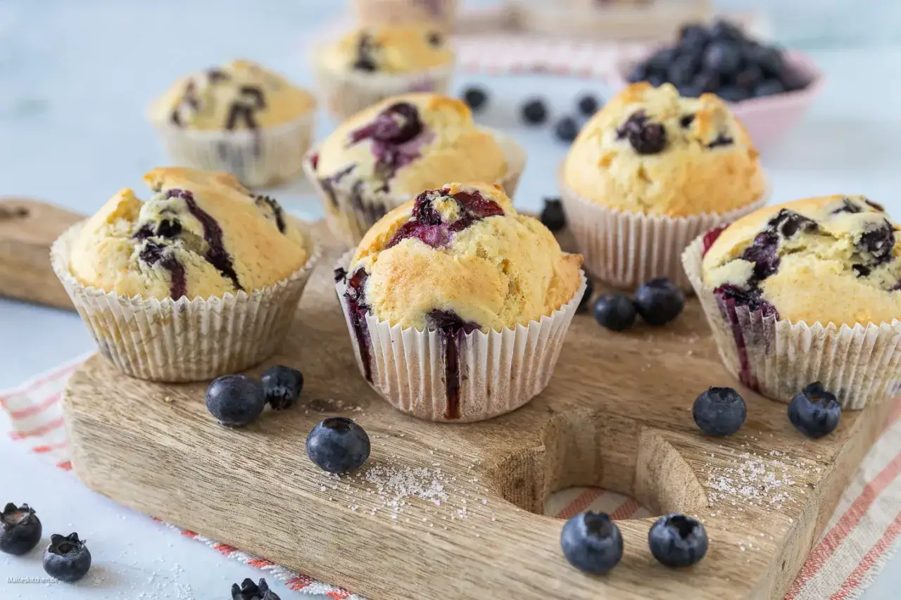 Frisch gebackene Blaubeermuffins, die das perfekte Muffins Grundrezept zeigen. Mit saftigen Blaubeeren und zartem Teig.