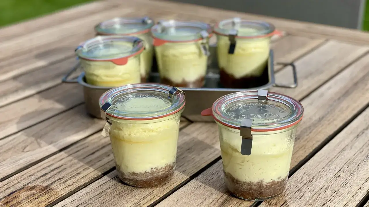 Sechs leckere cheesecake im glas stehen auf einem Holztisch.