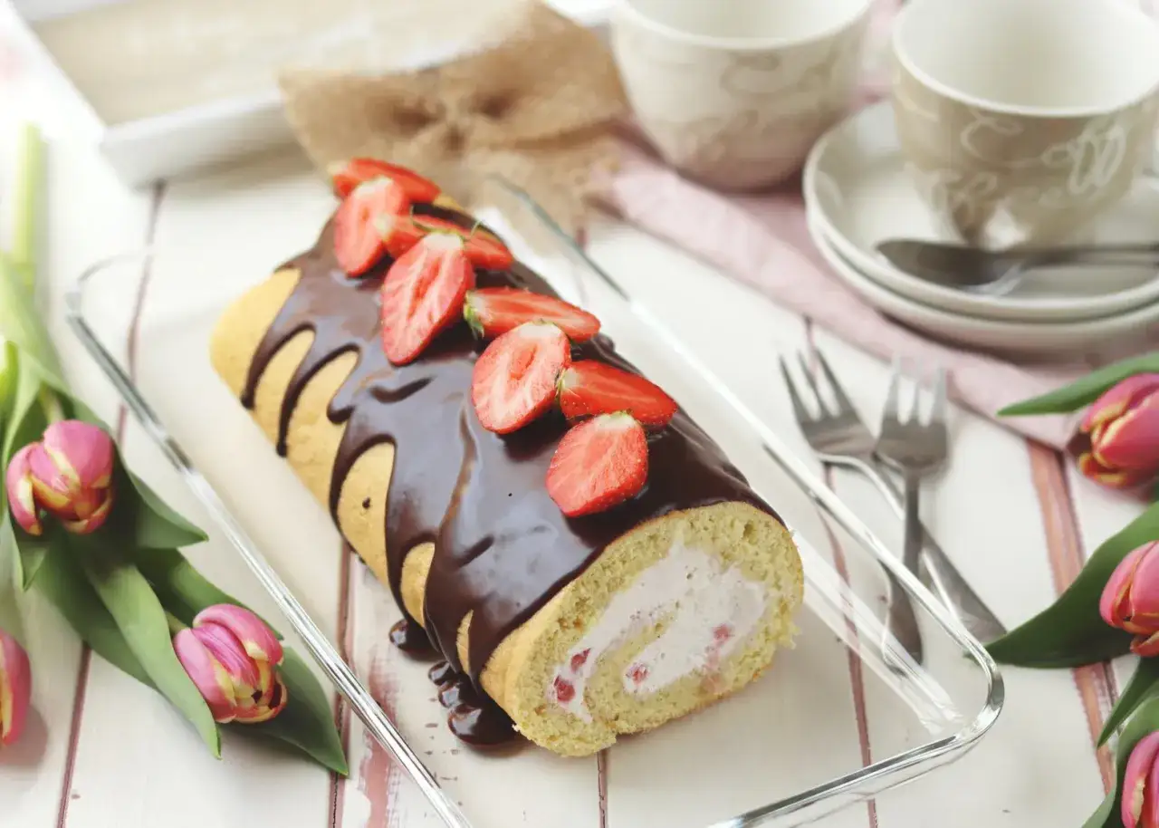 Schokoladen-Biskuitrolle mit Erdbeeren und Sahne, ein köstliches biskuitrolle rezept, dekoriert mit frischen Erdbeeren und Schokoladenglasur.