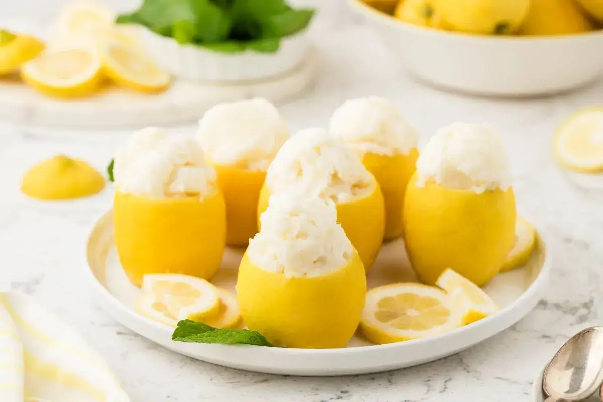 Erfrischendes Zitronensorbet-Rezept: Ganze Zitronen gefüllt mit cremigem Sorbet, garniert mit Minze und Zitronenscheiben.